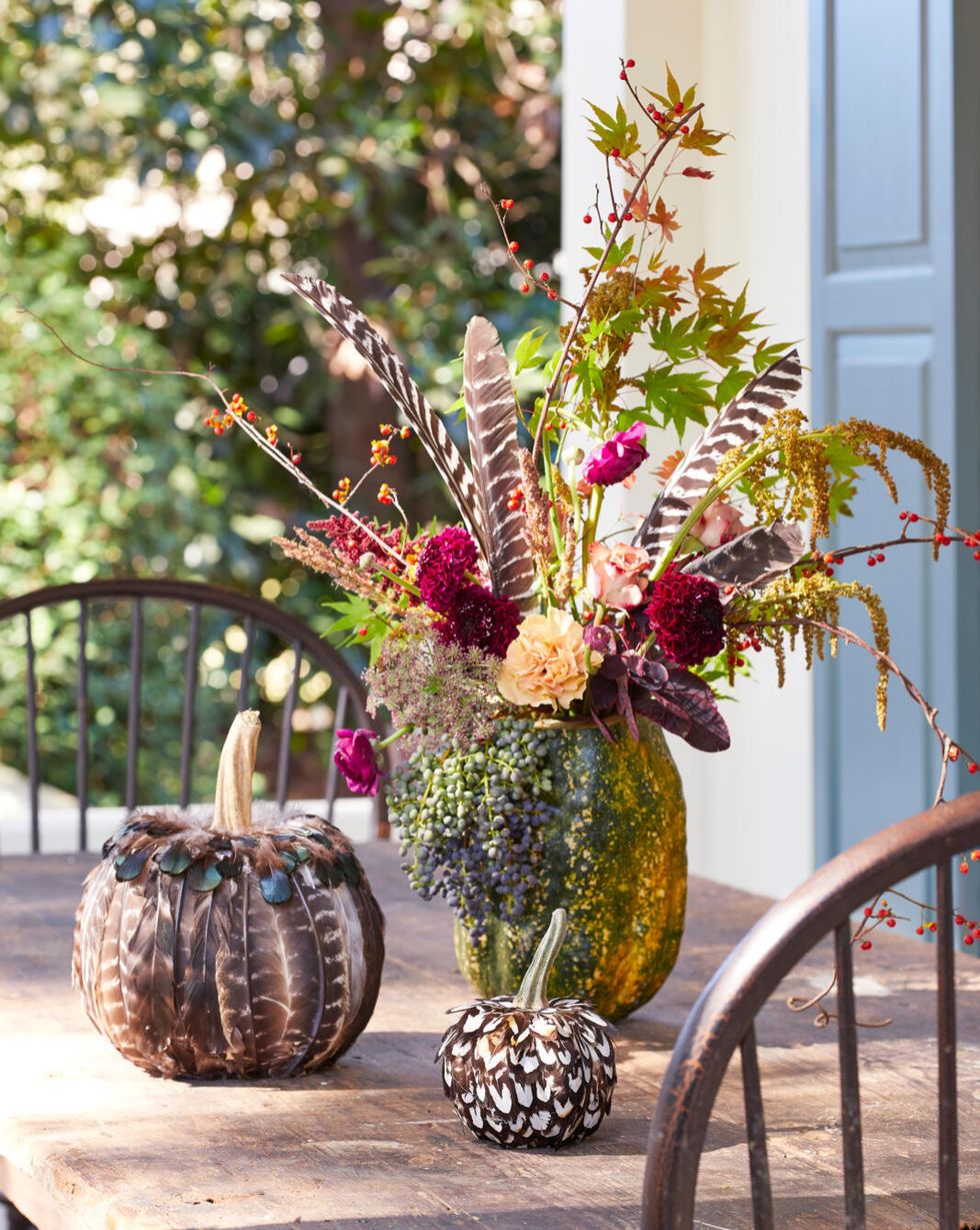 pumpkins decorated with feathers on an outdoor table