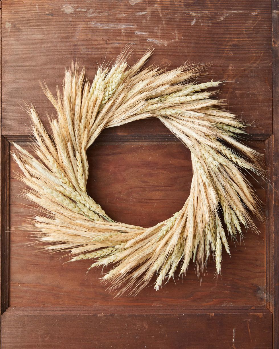fall wreath made from two different type of wheat hung on a brown door