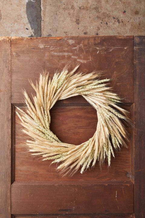 fall wreath made from two different type of wheat hung on a brown door