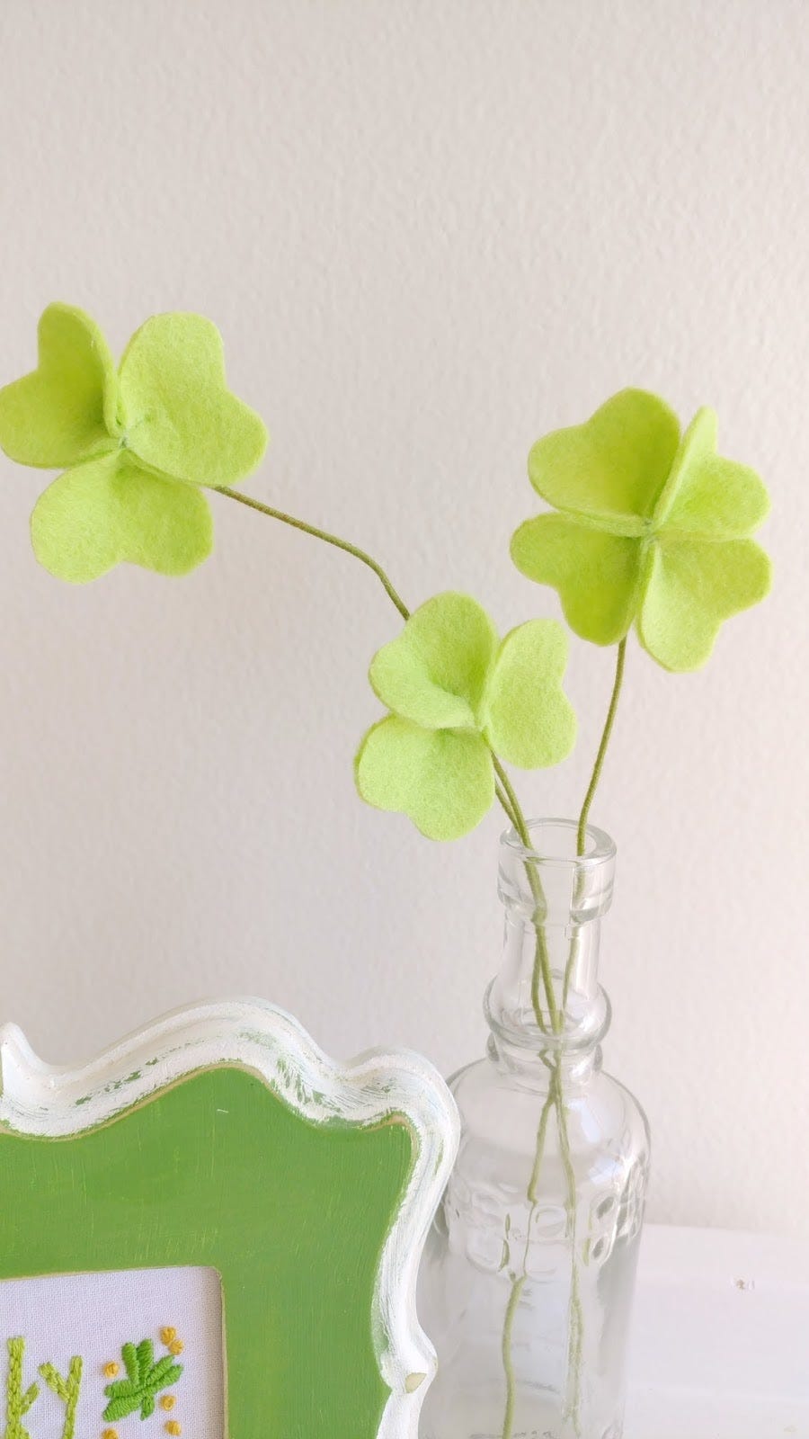 artificial green felt clovers displayed in a glass bottle