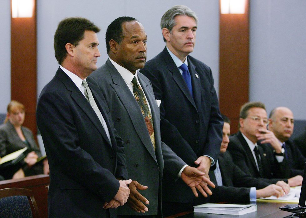 oj simpson standing between his lawyers inside a courtroom