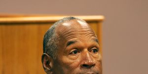 oj simpson sits and looks to the right, he wears a denim shirt