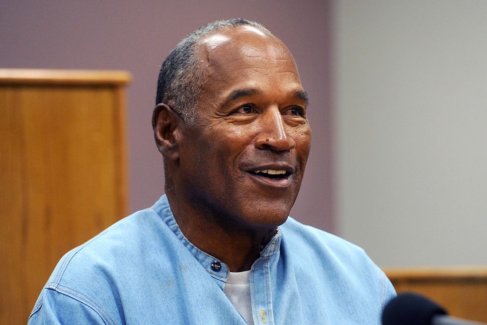 oj simpson smiles and looks to the right, he wears a denim shirt