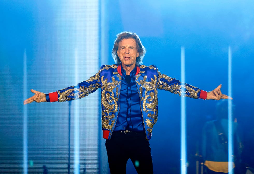 mick jagger stands on a stage with his arms outstretched as his sides