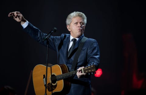 peter cetera playing guitar in front of a microphone