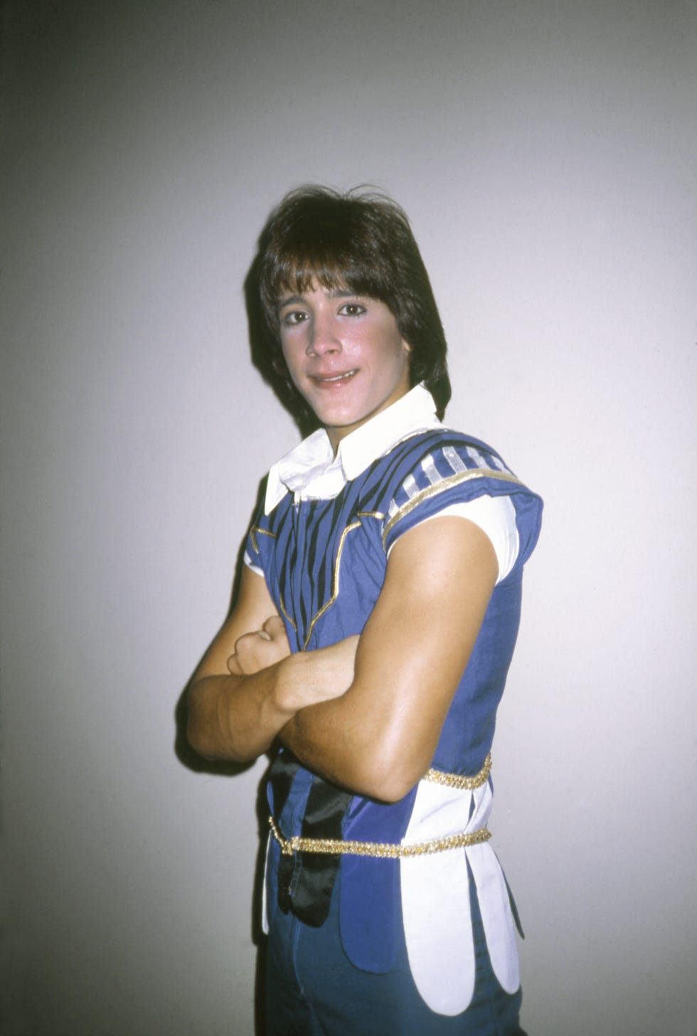 roy rossello wearing a blue sleeveless costume, folding his arms and smiling for the camera