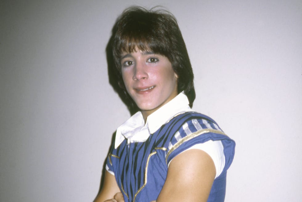 Singer Roy Rossello in 1985 roy rossello wearing a blue sleeveless costume, folding his arms and smiling for the camera