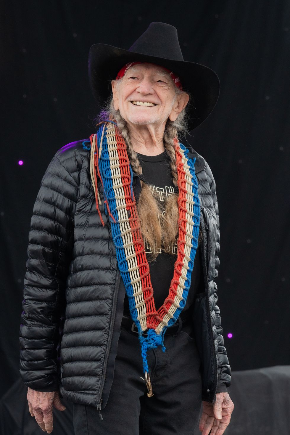 willie nelson wearing a cowboy hat and smiling as he looks into the crowd