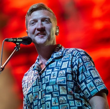 tyler childers smiling as he looks out into a crowd with a red background