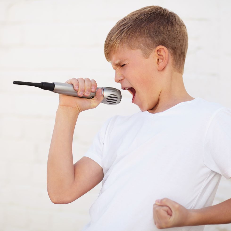 a boy sings emphatically into a microphone