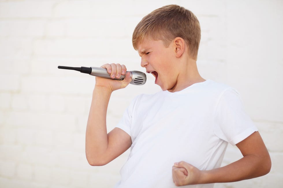 a boy sings emphatically into a microphone