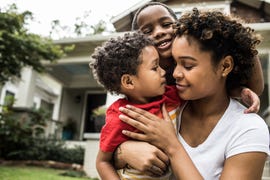 single mother playing with young sons in front of house