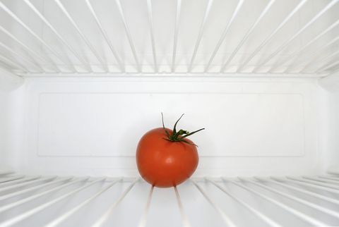 single red tomato sitting on shelf inside refrigerator