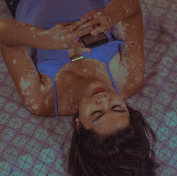 woman laying in bed while using her telephone