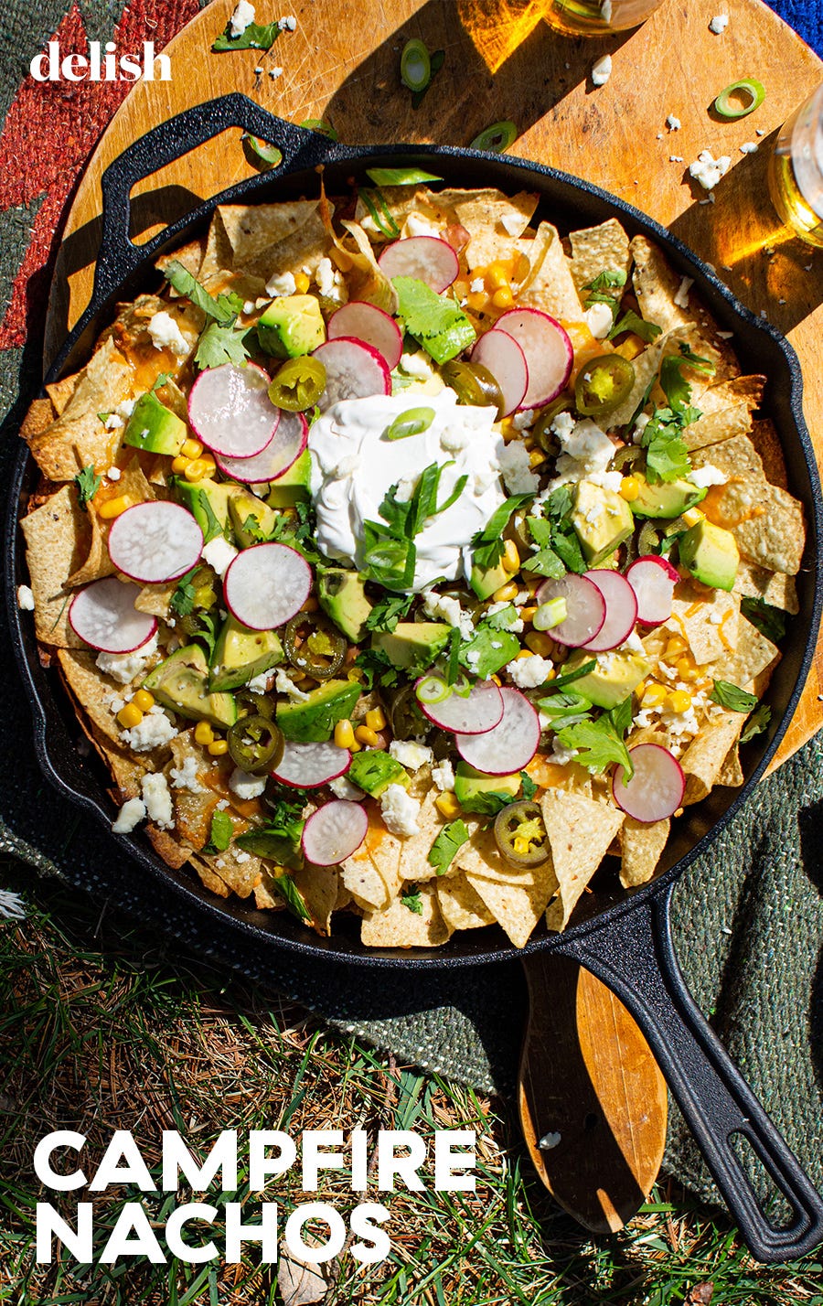 nachos in a skillet topped with corn, cilantro, and sour cream