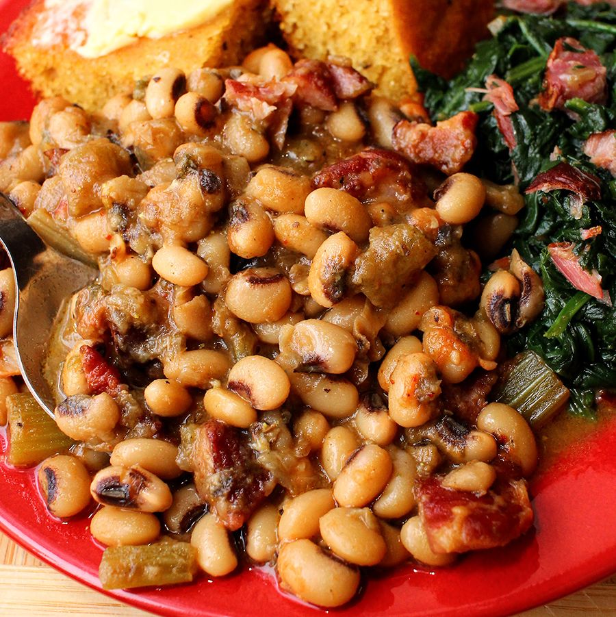 stewed black eyed peas on a red plate, alongside greens and buttered cornbread