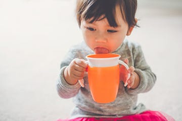 a toddler girl drinks from her sippy cup