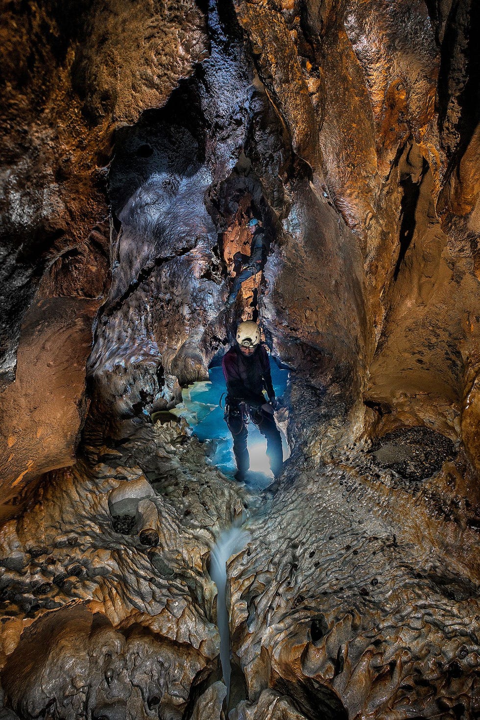 Een lid van de expeditie loopt door het gedeelte van het Sistema Huautla dat achter een van de ondergelopen passages van de Skeleton Canyon ligt Wie zich door de canyon verplaatst moet over messcherpe rotsen lopen die onder het gewicht van een klimmer gemakkelijk kunnen afbreken Om deze foto van de verlichte grot te kunnen maken voegde de fotograaf meerdere opnamen met verschillende sluitertijden samen