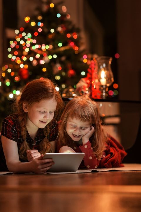 sisters using tablet pc on floor during christmas