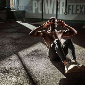 african american male athlete exercising sit ups with hands behind his head in a gym copy space