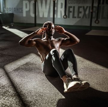 african american male athlete exercising sit ups with hands behind his head in a gym copy space