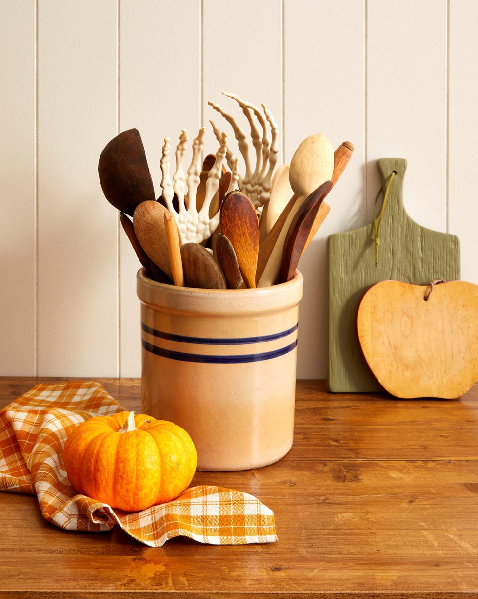 fake skeleton hands tucked into a kitchen crock with wooden spoons set on a kitchen counter fake skeleton hands tucked into a kitchen crock with wooden spoons set on a kitchen counter