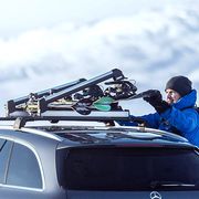 man adjusting snowboard on car roof rack