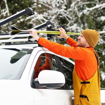 man securing skis to top of car with ski rack
