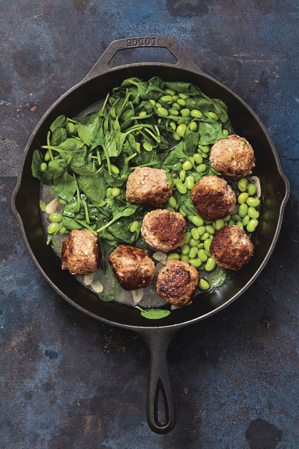 skillet meatballs wit spinach and peas in a cast iron pan