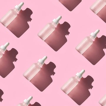 skin care pattern made with bottles with beauty product facial serum or essential oil on pastel pink color background