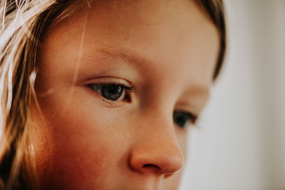 part of a childs face, with close up and focus on the childs nose and eyes her complexion is perfect and light freckles are visible