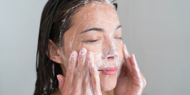 Skincare woman washing face in shower