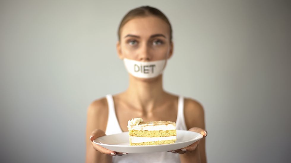 skinny girl with taped mouth holding cake, refuses to eat sweet, low carb diet