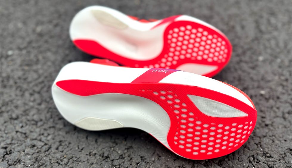 a pair of red running shoes turned on their side showing a red and white outsole pattern