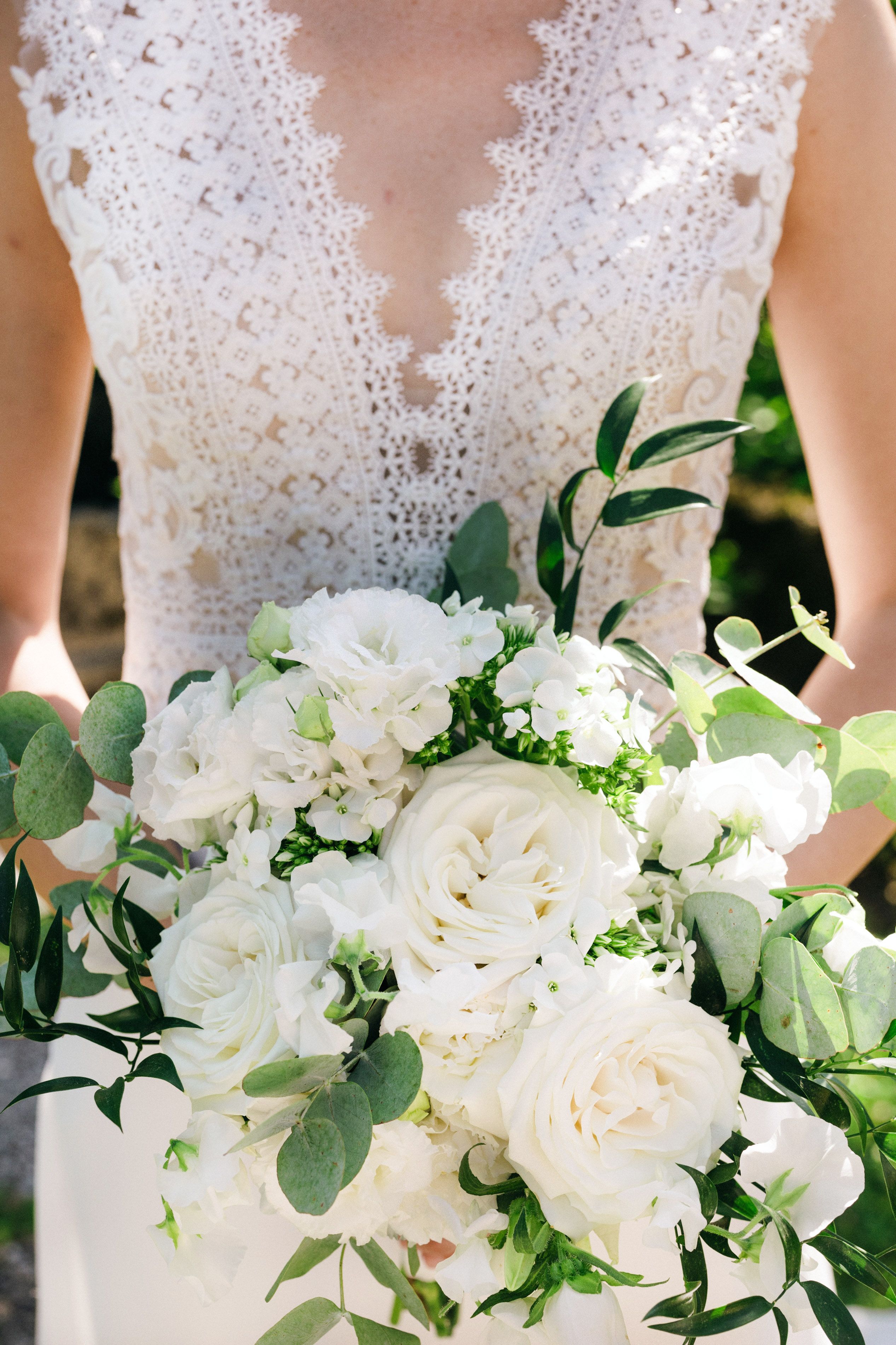 La sposa in una corona con un bouquet si erge su un tappeto bianco vicino a  un arco nuziale