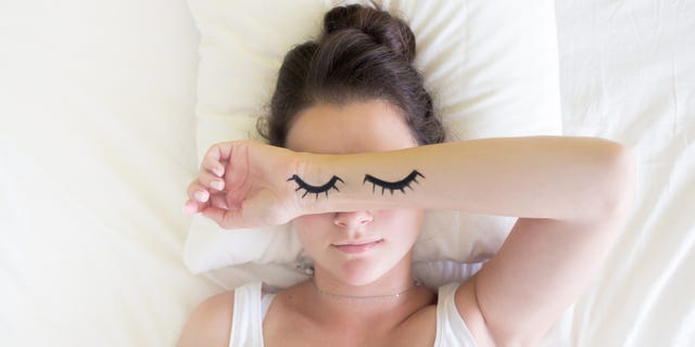 Painted sleeping eyes and brunette young woman in the bed at morning time