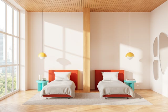 minimalist bedroom with two orange single beds, pendant lamps, and a wooden pillar, large window with a city view, cozy and modern concept. 3d rendering; shutterstock id 2536324181; magazine_title_and_month: gh digi sleep divorce; ordered_by: jodie anderson; client: