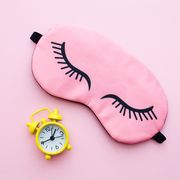 pink sleep mask and yellow alarm clock on pink background