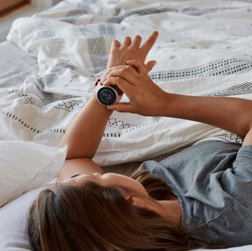 een vrouw ligt in bed en bedient haar horloge