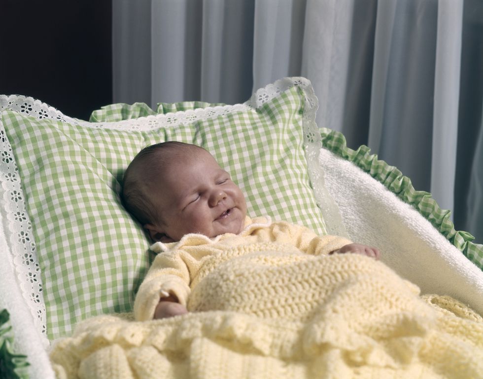 sleeping baby in bassinet with yellow blanket green and white pillow