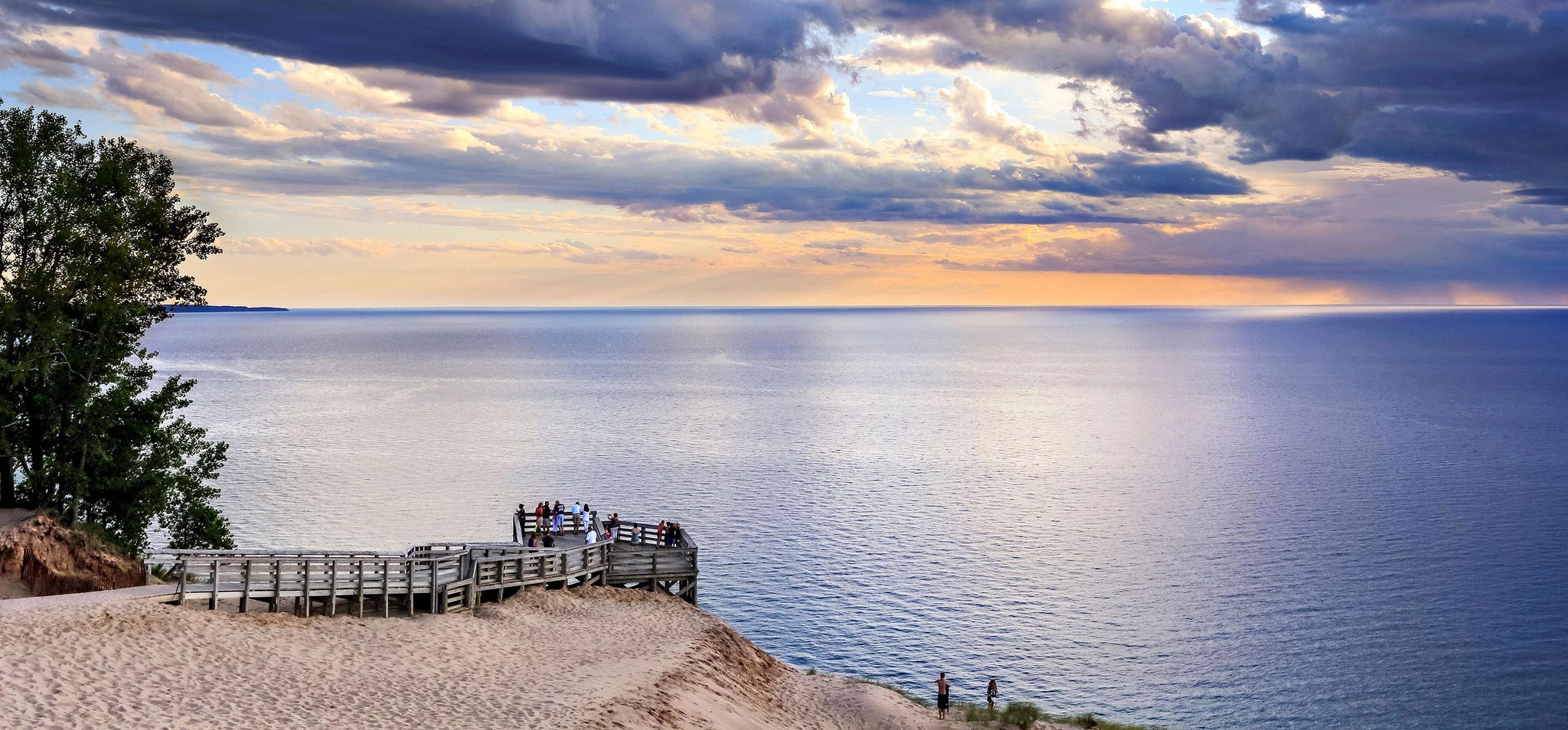 Bij de Lake Michigan Overlook in de Sleeping Bear Dunes Michigan kijken bezoekers vanaf een houten steiger uit over het weidse blauwe water