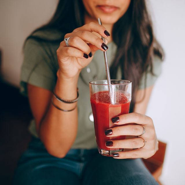 a woman drinking red juice from a straw
