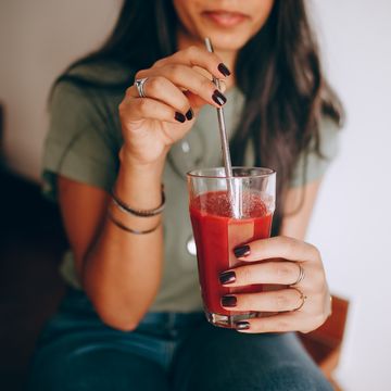 a woman drinking red juice from a straw