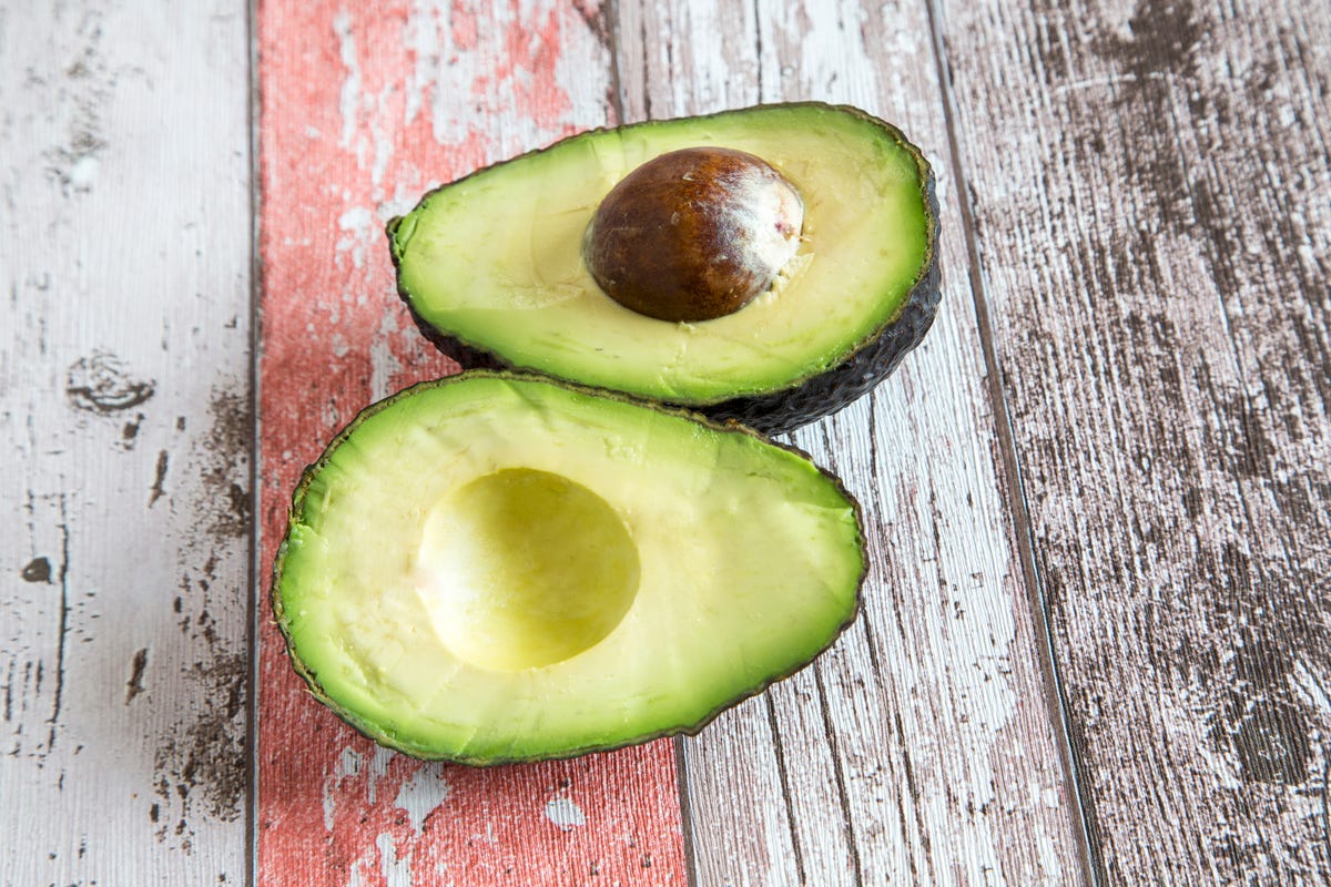 Royalty-Free photo: Avocado fruit on chopping board beside green handled  knife