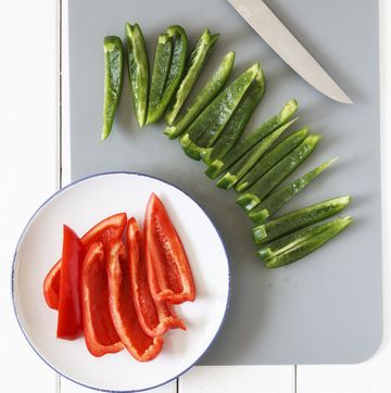 sliced red and green ball peppers, knife and kitchen board, elevated view