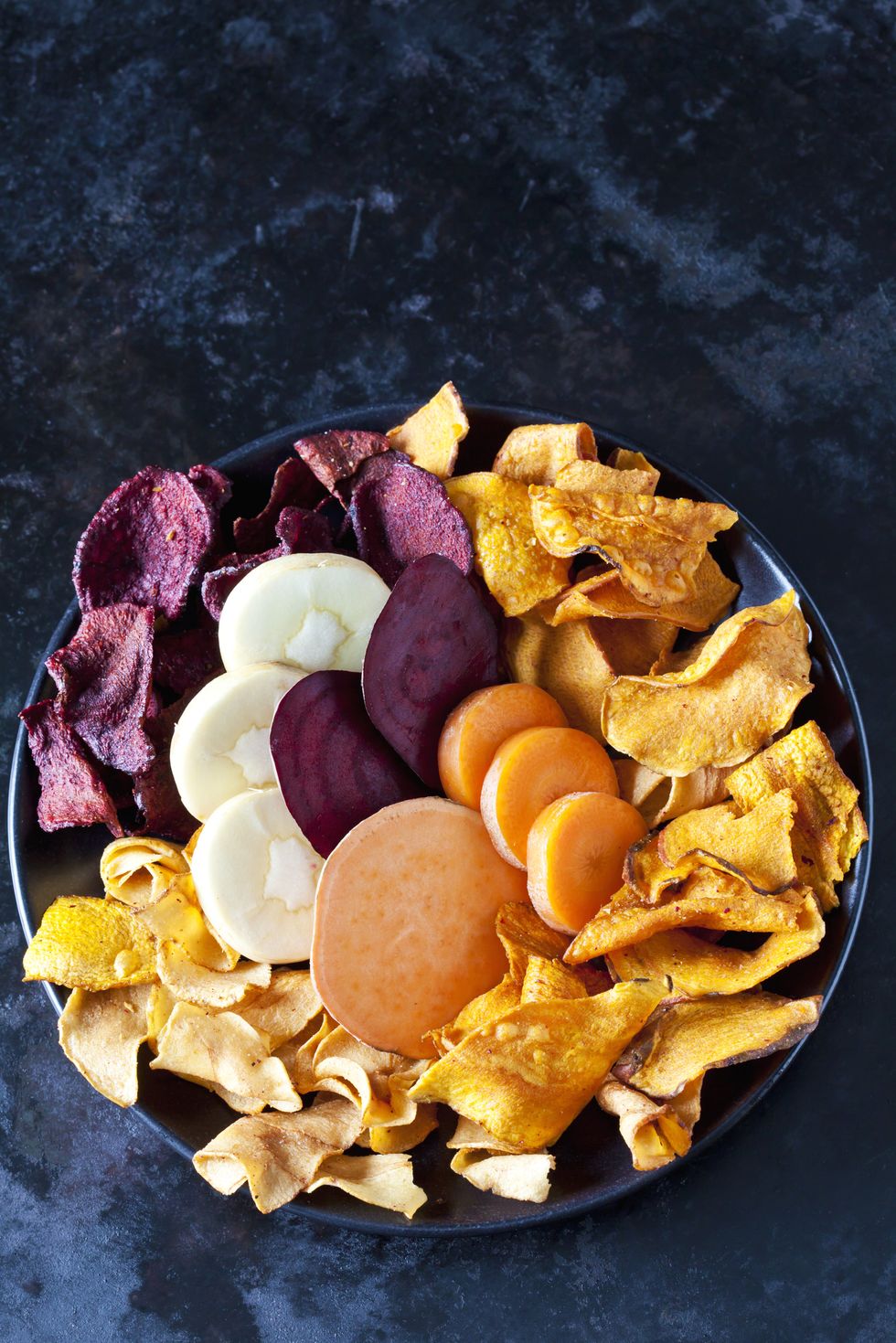 Sliced root vegetables and vegetable chips in bowl
