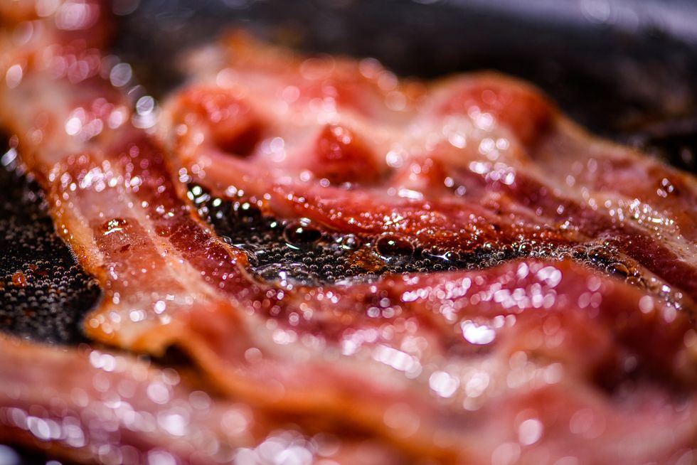 slices of pork bacon being fried on a pan extreme close up shoots