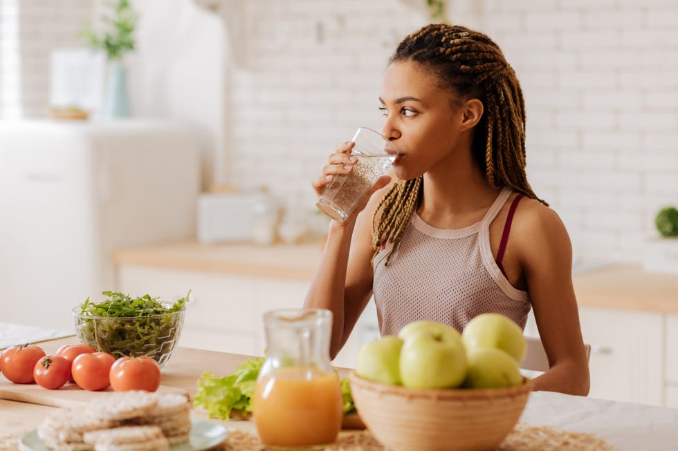 slim and fit woman drinking water before having breakfast