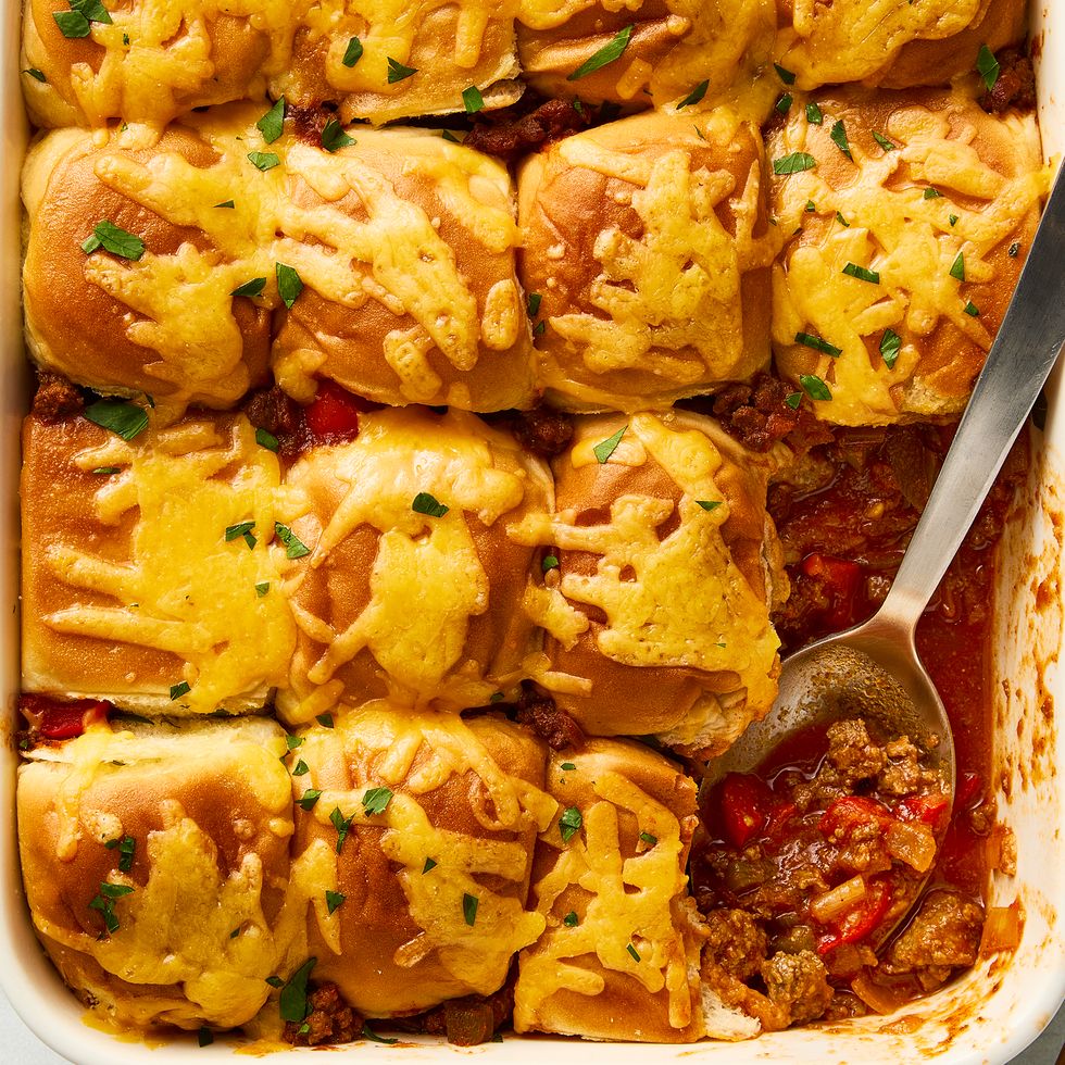 Casserole dish filled with Sloppy Joe mix topped with mini buns and melted cheese