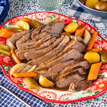 slow cooker brisket recipe on red floral platter with carrots and potatoes
